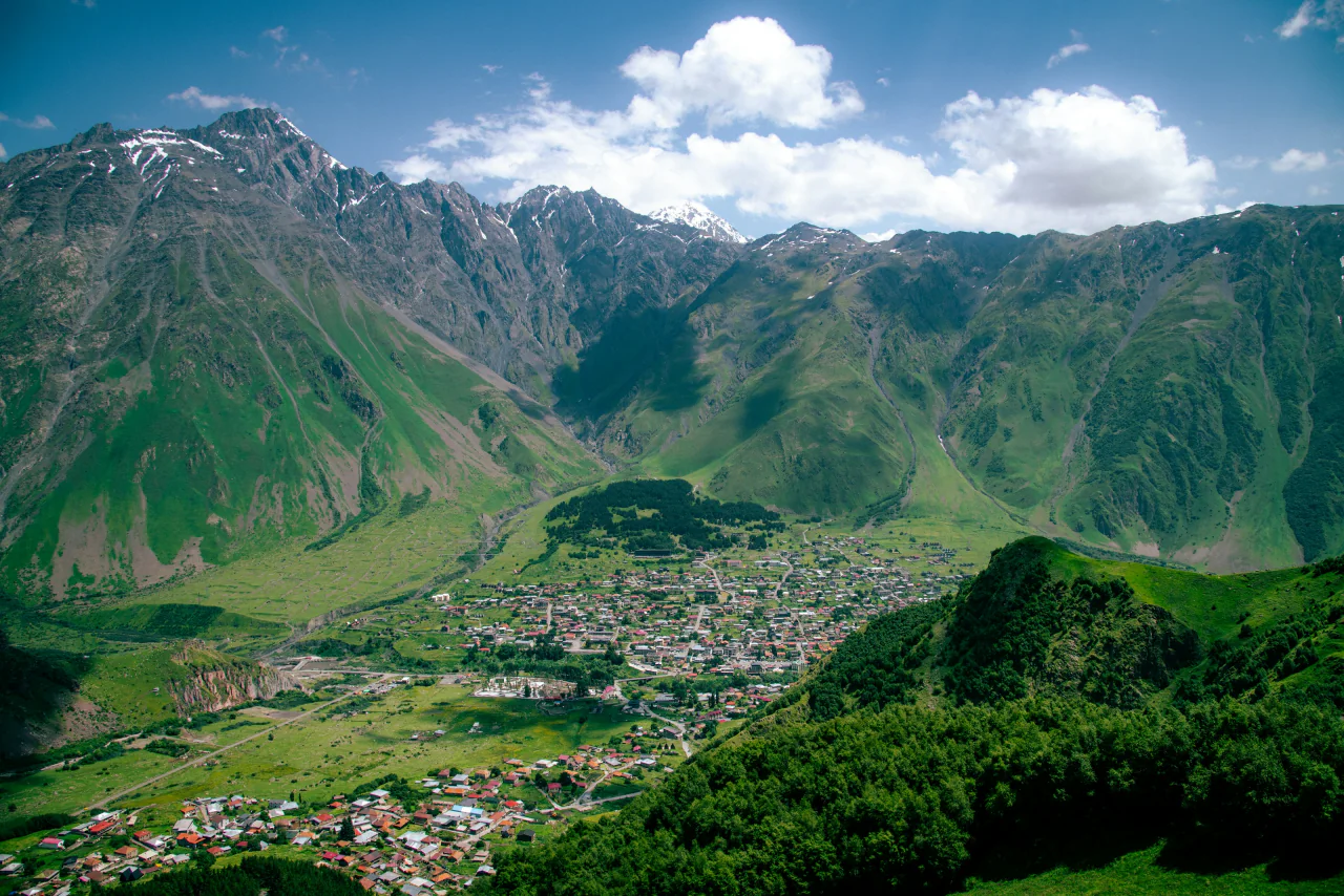 A town in a green valley beneath the Greater Caucasus range