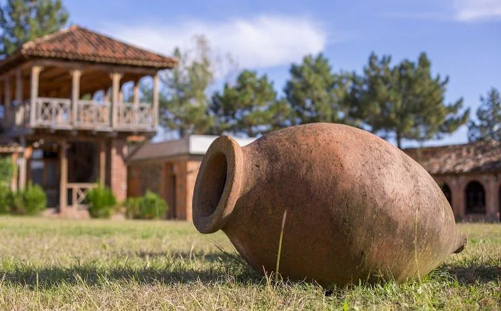 A clay qvevri resting on the grass outside a traditional Georgian marani